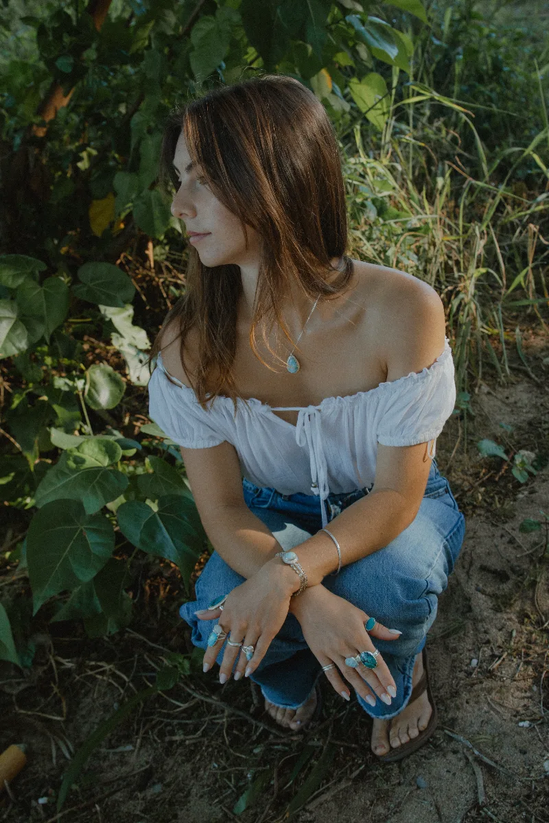 Model looking down, wearing silver drop earrings and rings