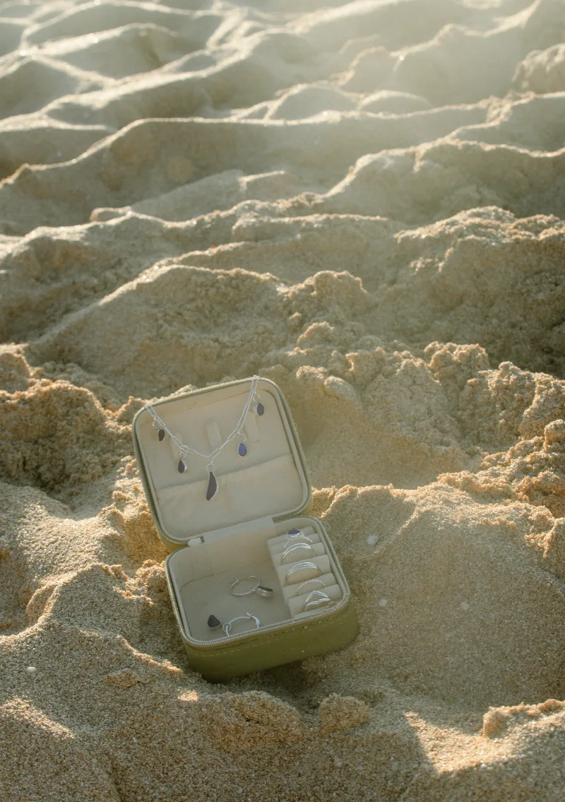 A hand drawing in wet sand, wearing silver rings and bangles